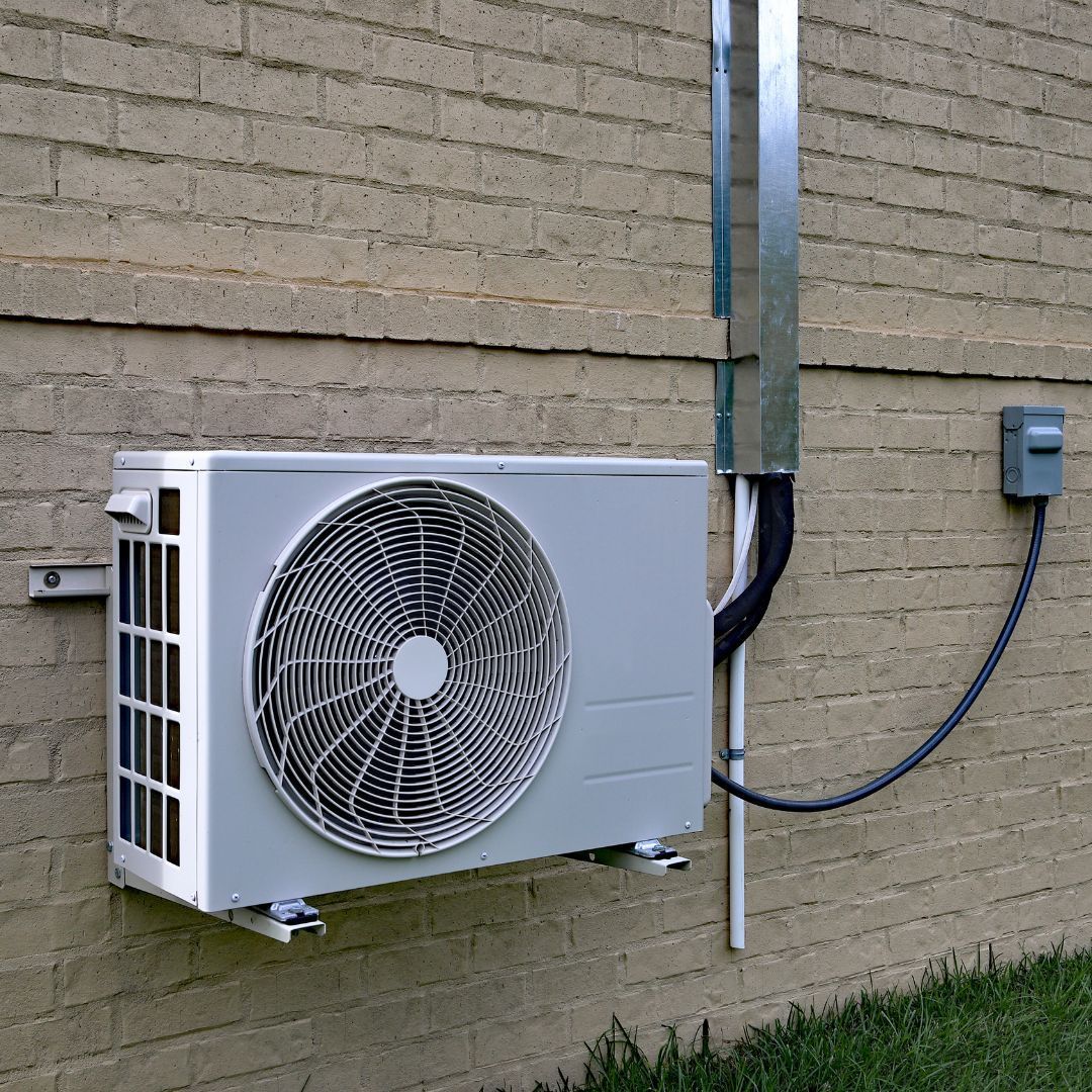 A fan is attached to the side of a brick building