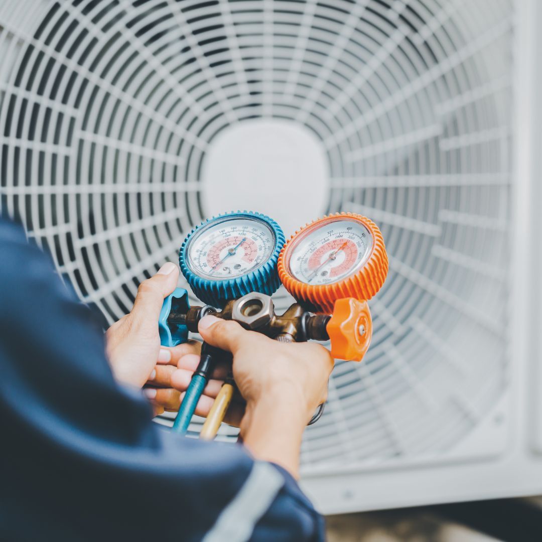 A person is holding a gauge in front of a fan.