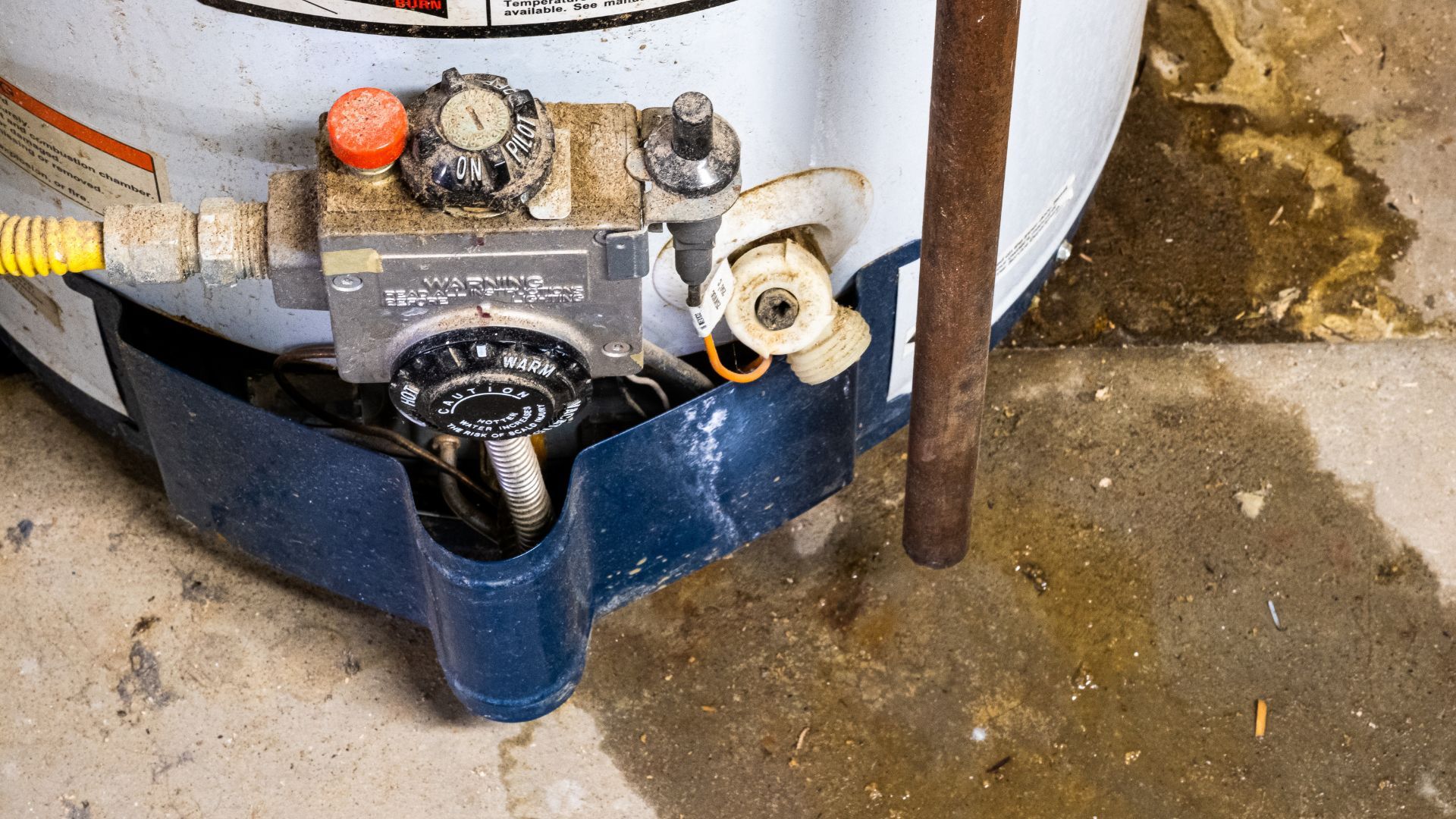 A water heater is sitting on the floor in a basement.