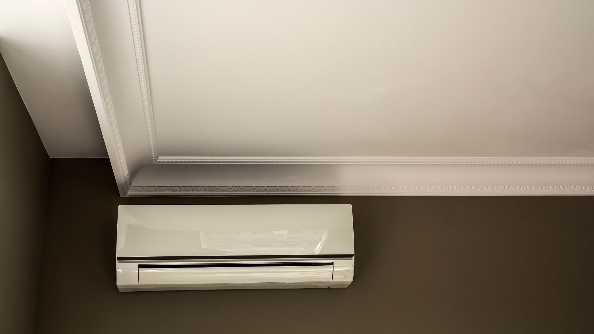 A white air conditioner is hanging from the ceiling in a room.