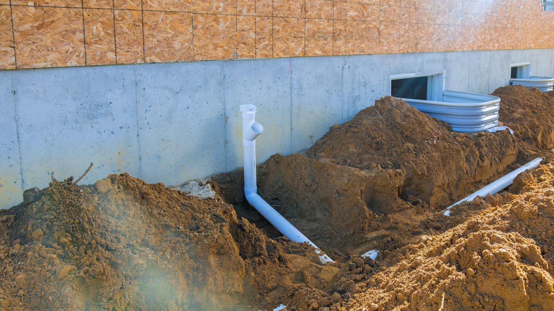 A drain pipe is being installed on the side of a house.