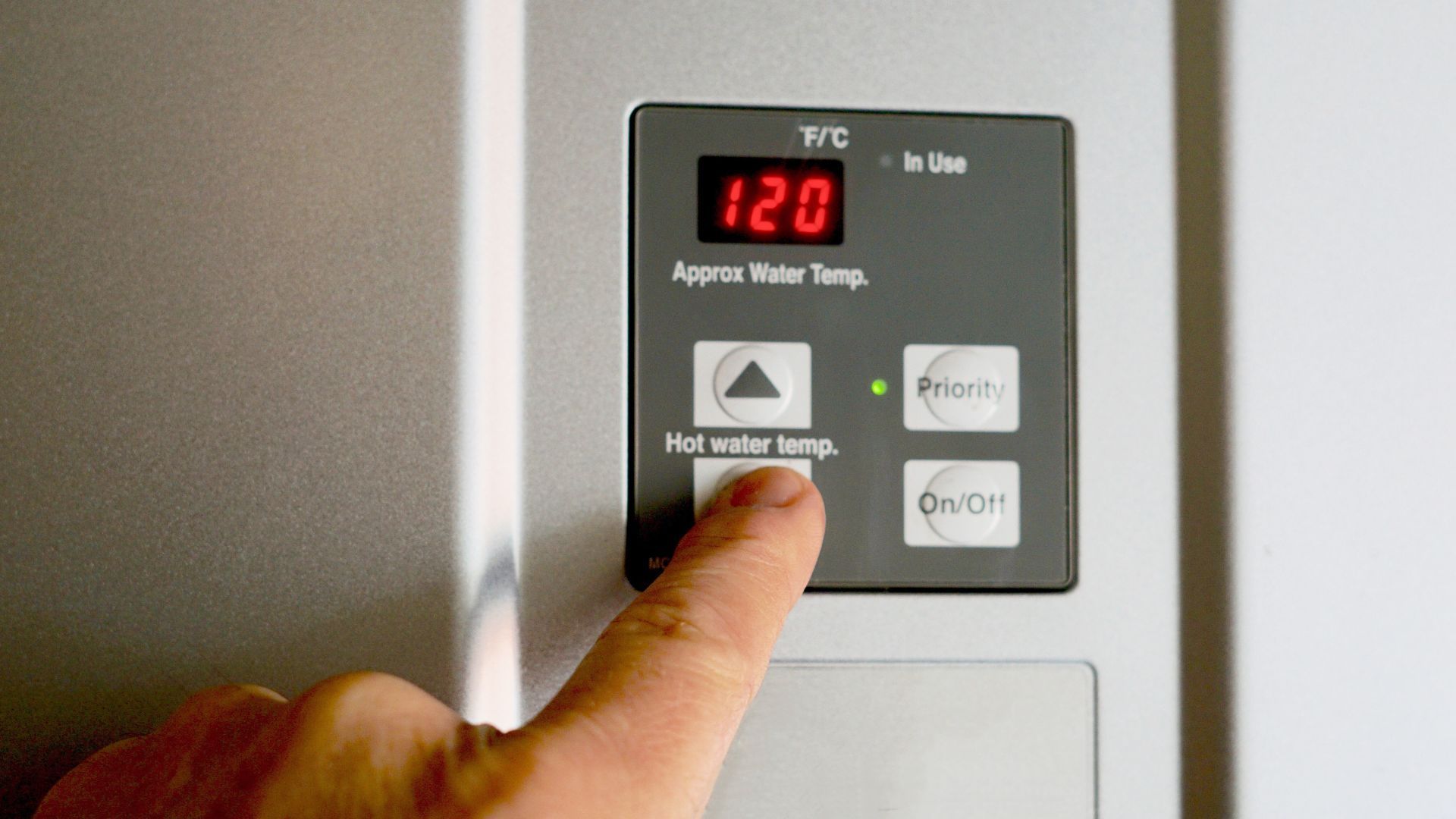 A person is pressing a button on a thermostat that reads 420