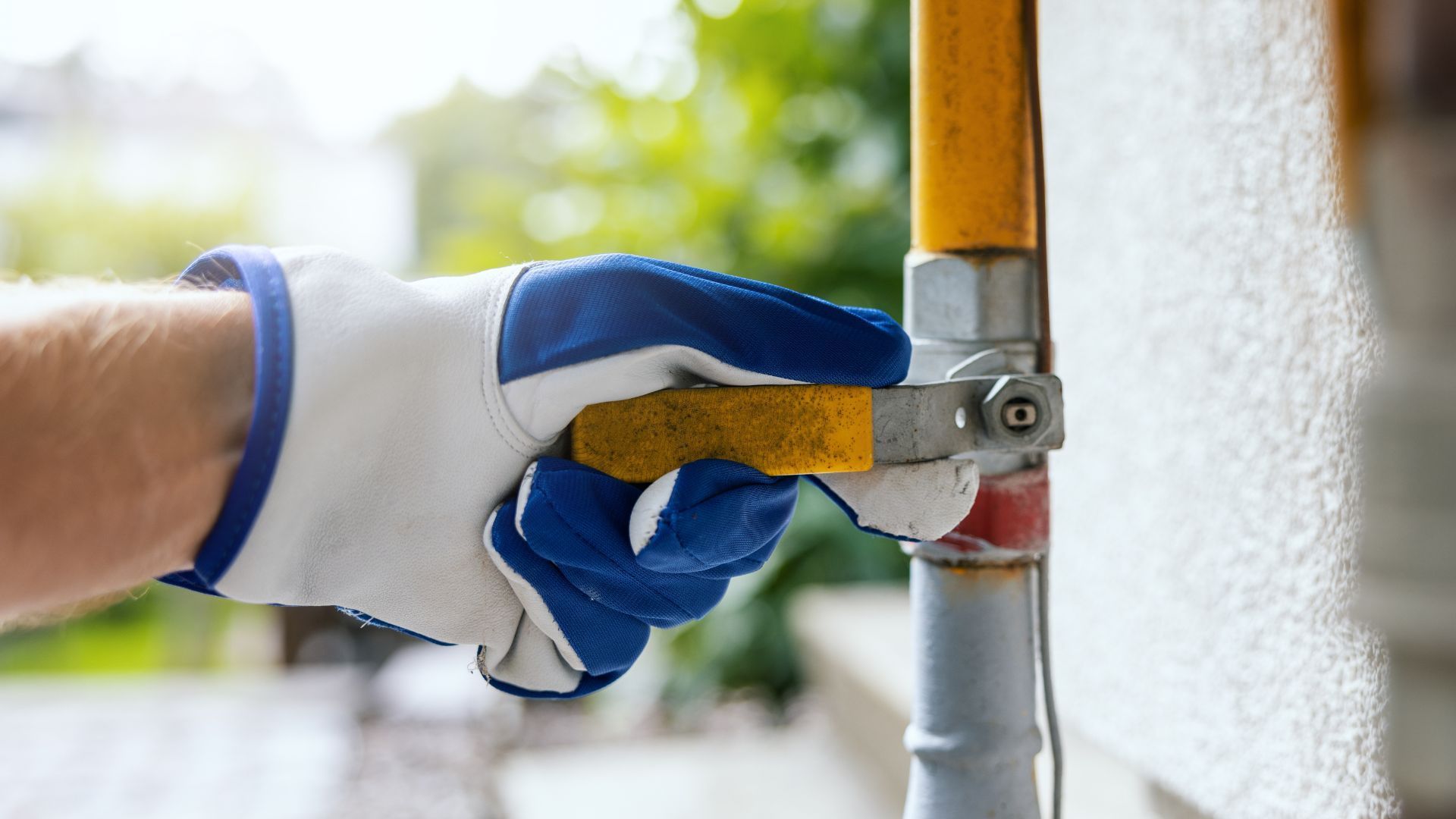 A person is using a wrench to open a gas valve on a pipe.