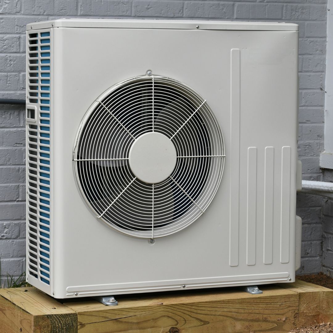 A white air conditioner is sitting on top of a wooden box.