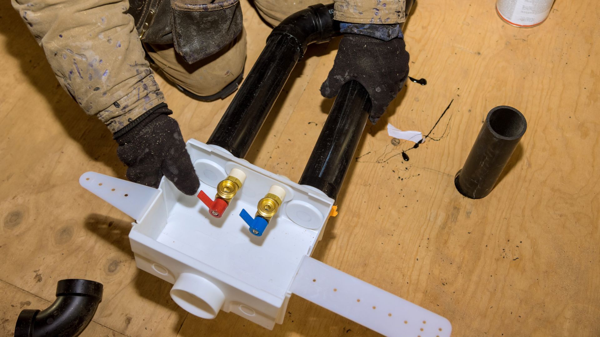 A plumber is working on a drain on the floor.