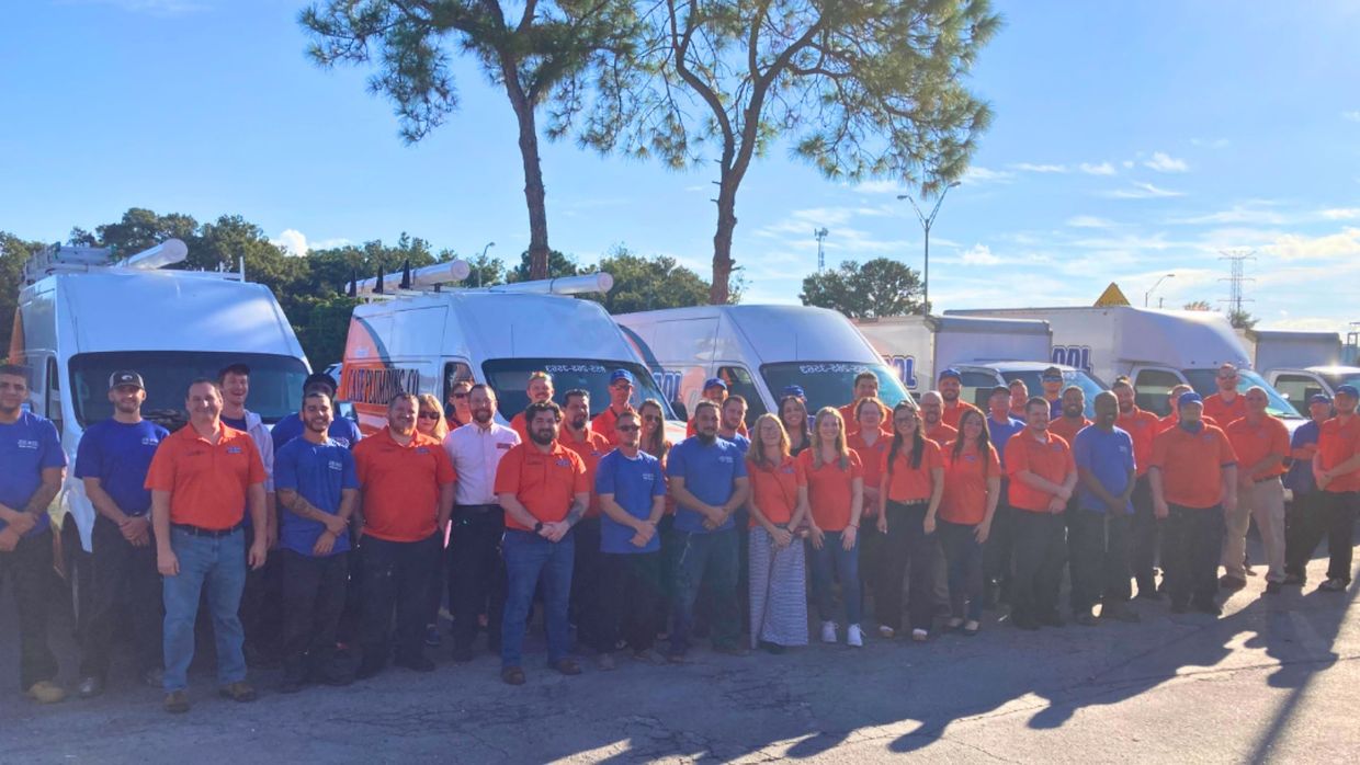 A large group of people standing in front of a row of vans.