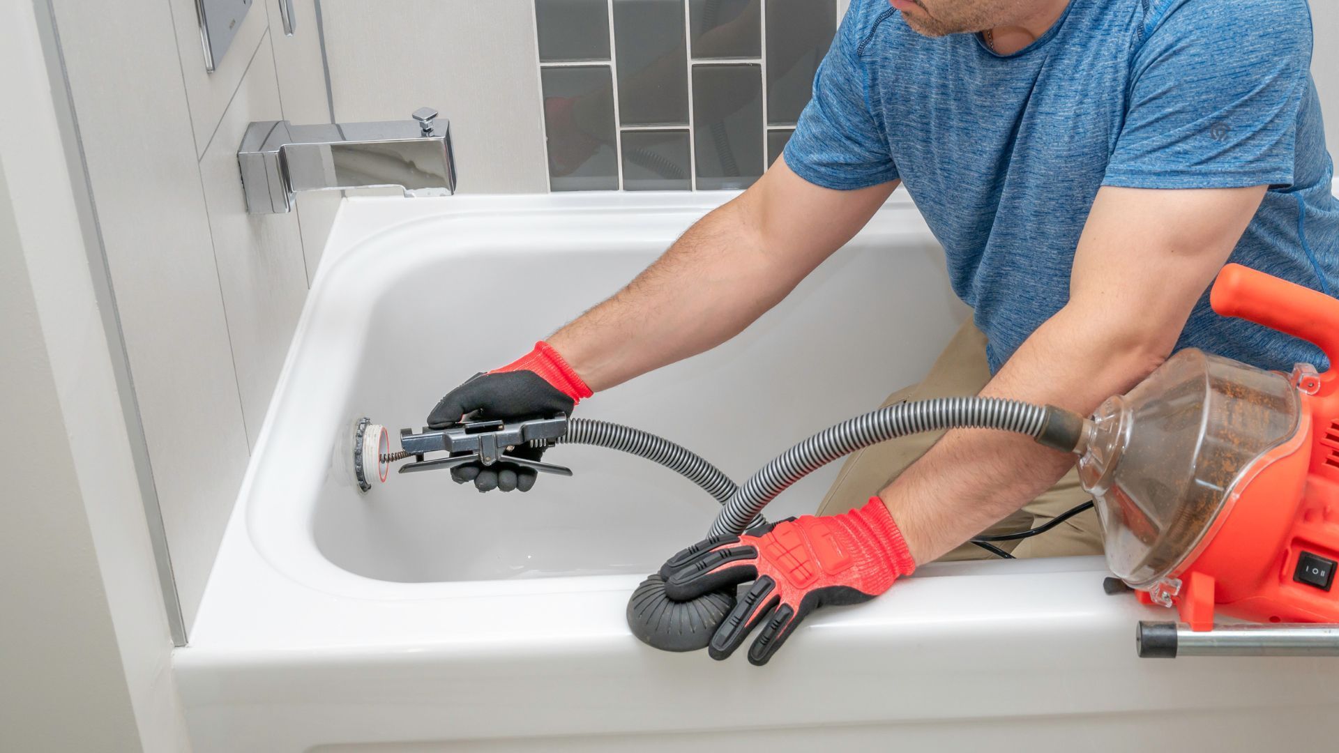 A man is cleaning a bathtub with a machine.