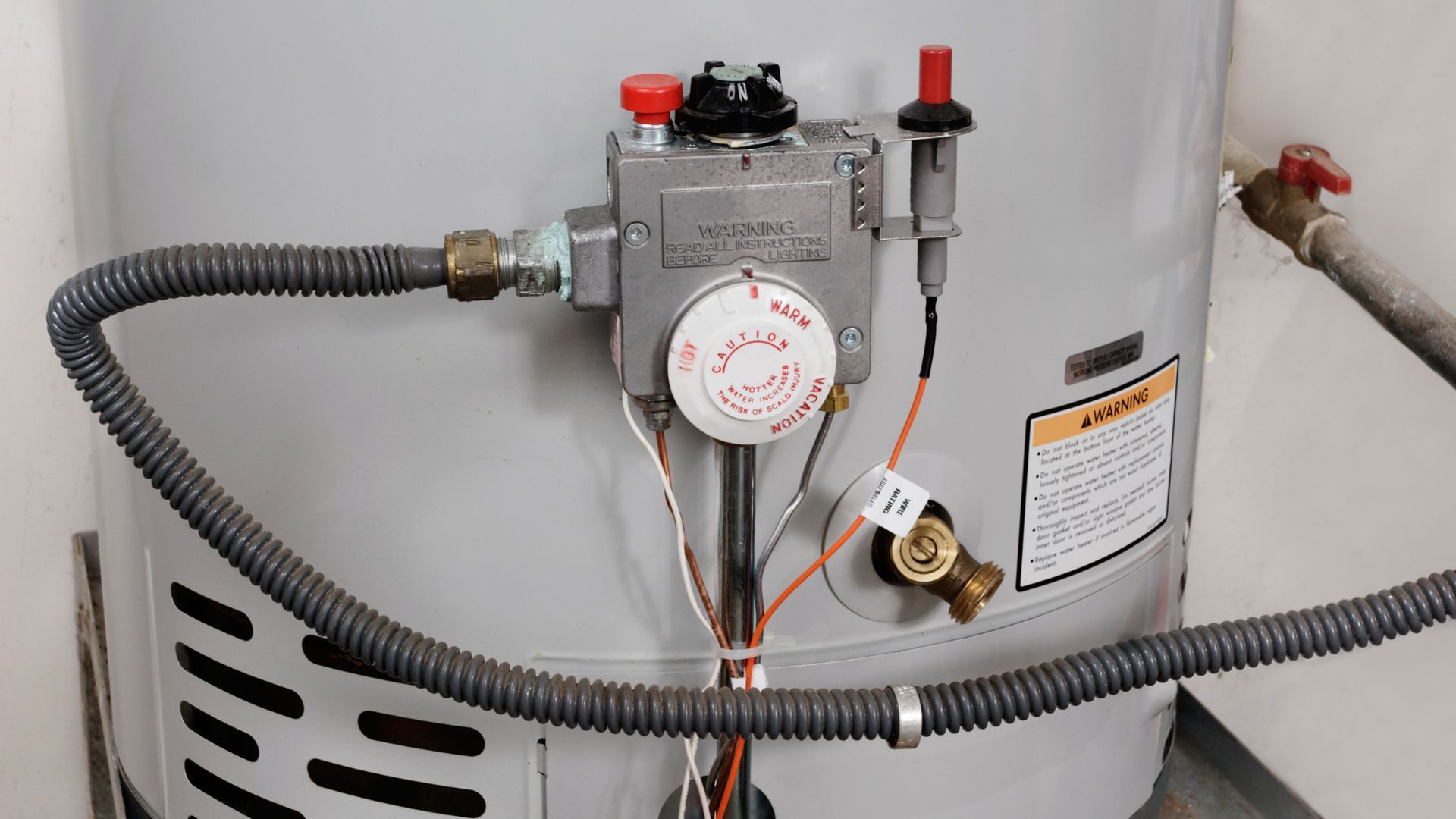 A close up of a water heater with a hose attached to it.