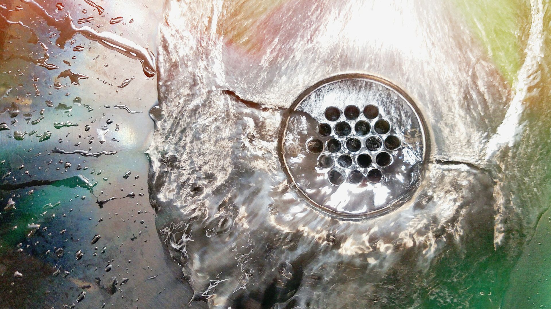A close up of a sink drain with water coming out of it.