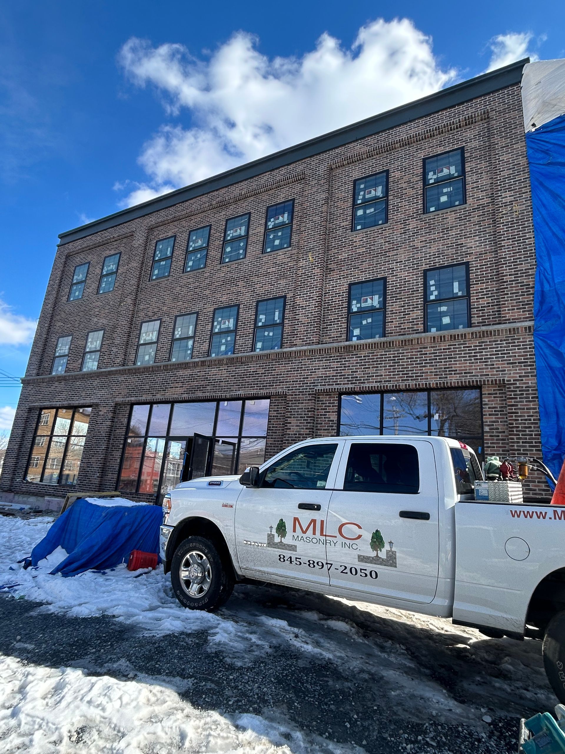 A white truck is parked in front of a large brick building.