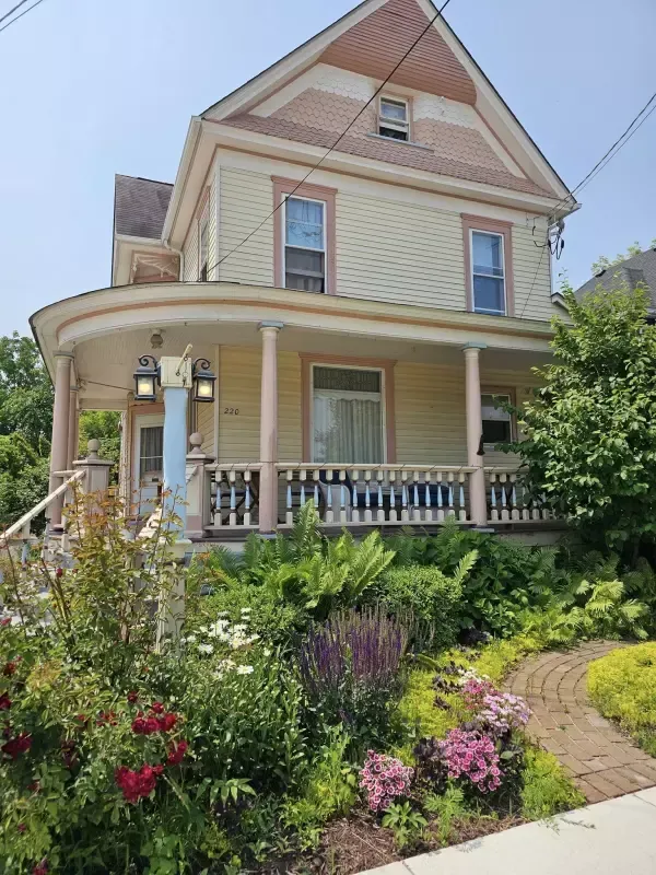 A large house with a porch and flowers in front of it