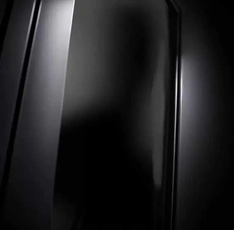A close up of a black door with a light coming through it.