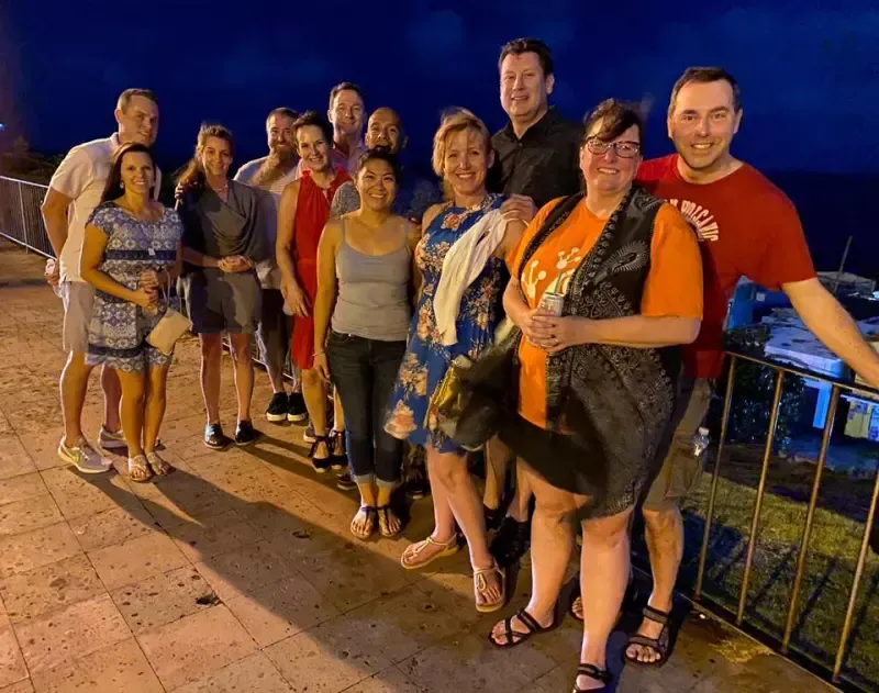 A group of people are posing for a picture on a balcony at night.