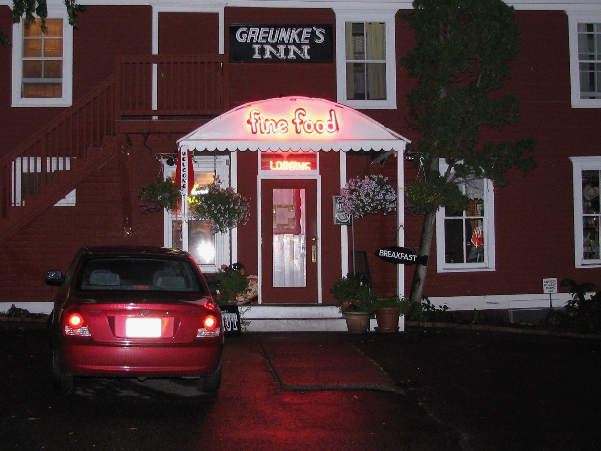 A red car is parked in front of a building that says griffin 's inn