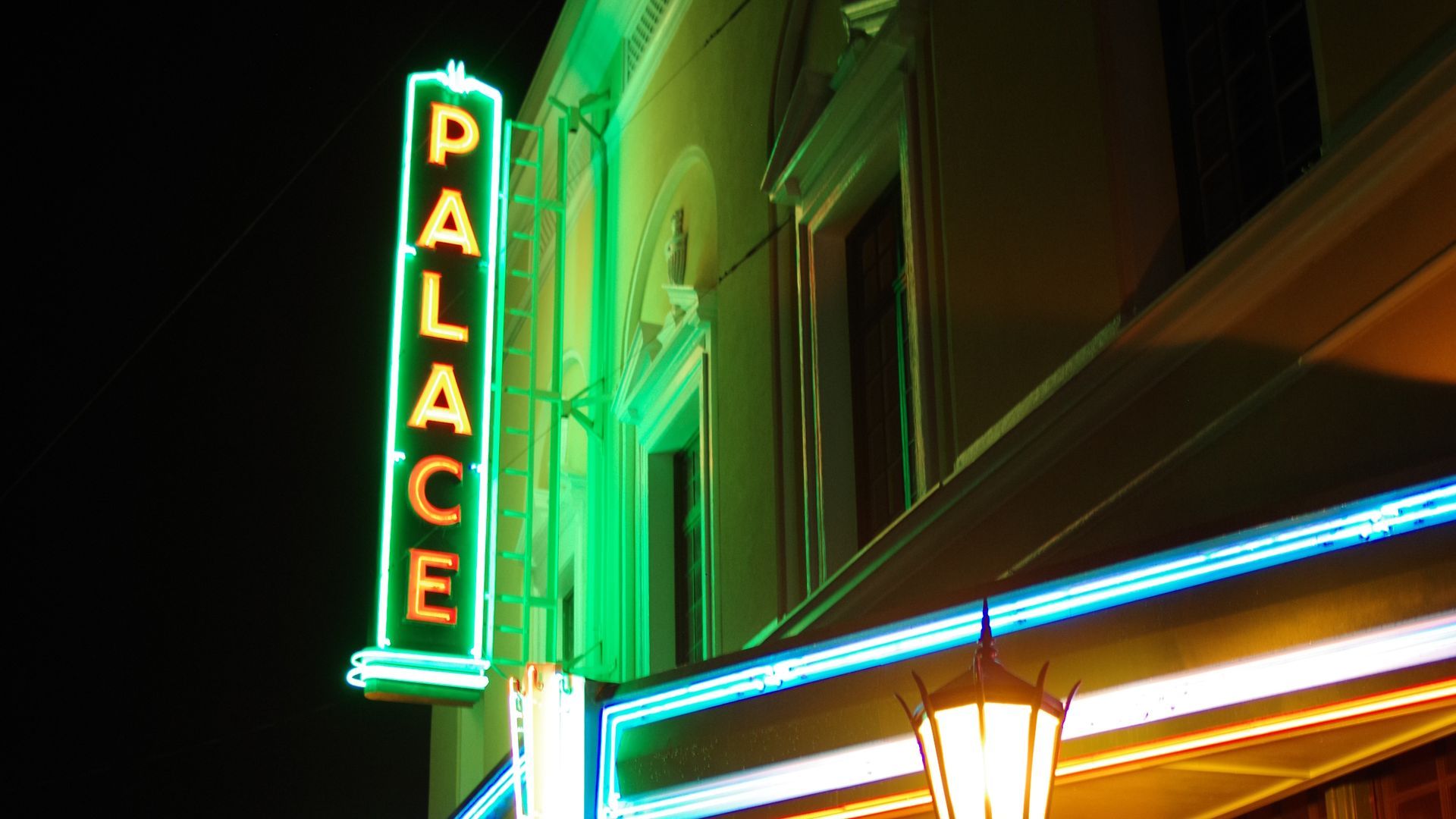 A neon sign for the palace theater is lit up at night
