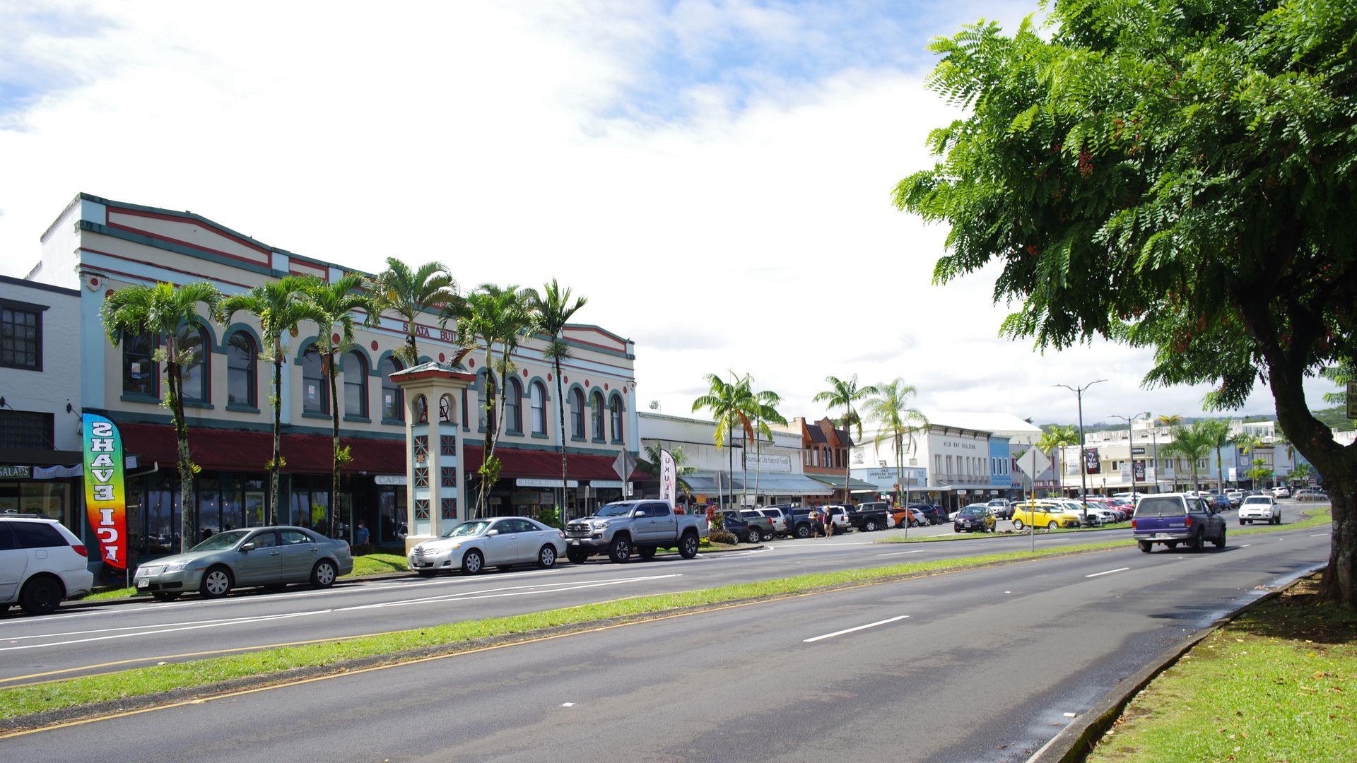 Cars are parked on the side of the road in front of a building that says fresh