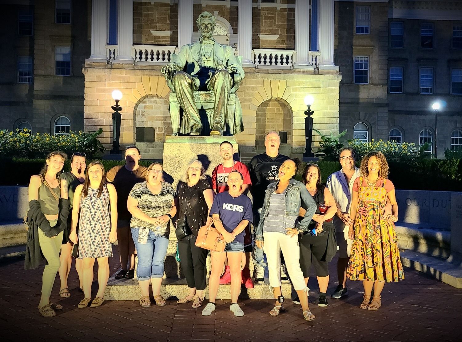 A group of people standing in front of a building with a statue in the background