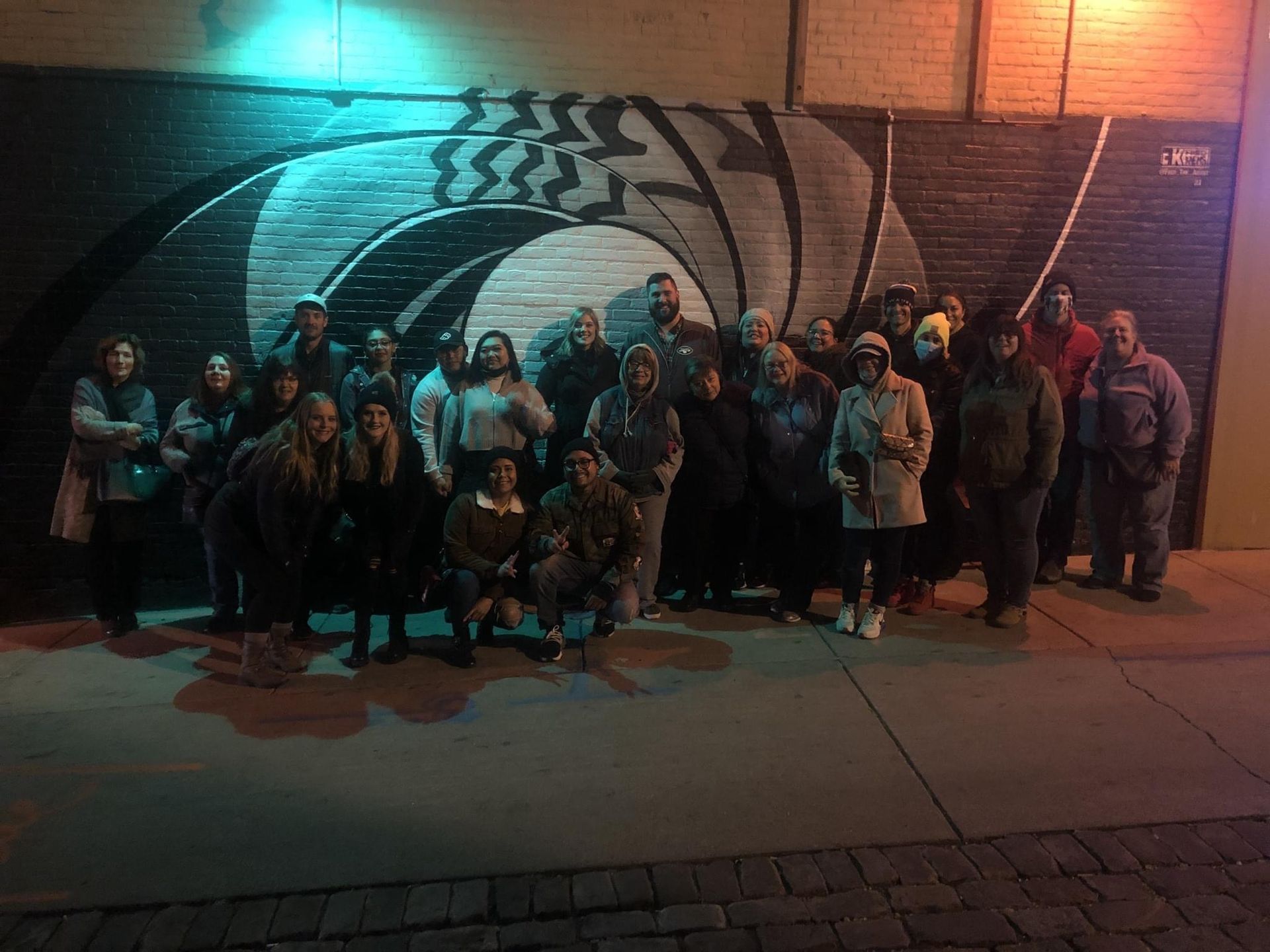 A group of people are posing for a picture in front of a graffiti wall