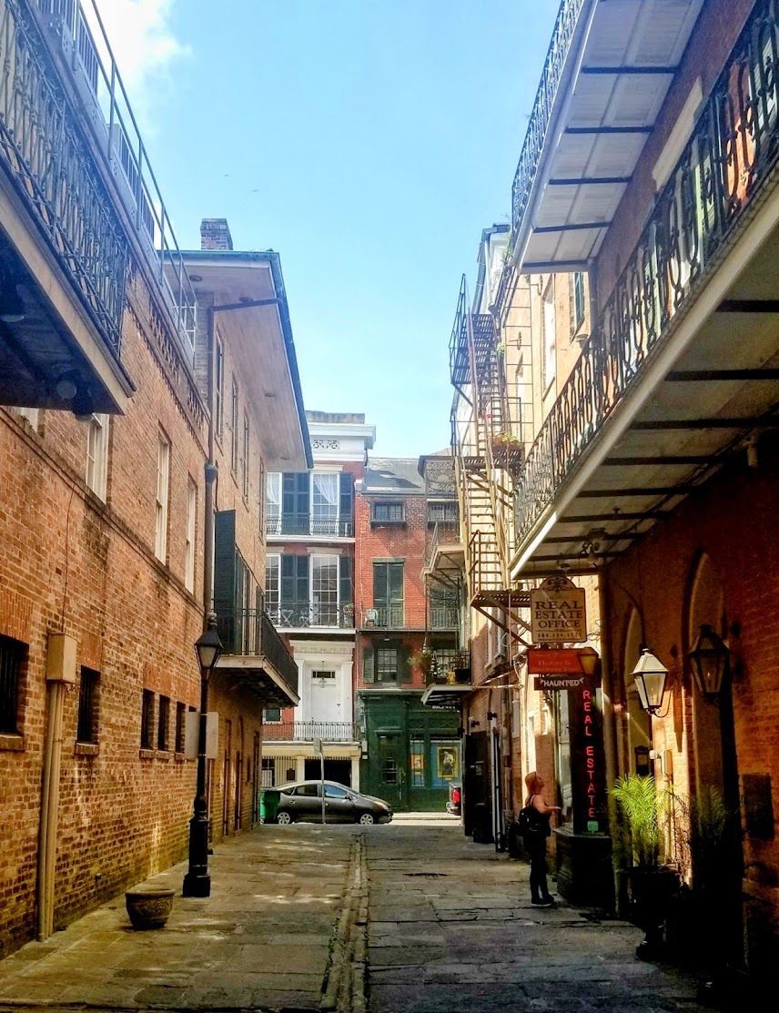 A narrow alleyway between two brick buildings with a sign that says ' french quarter ' on it