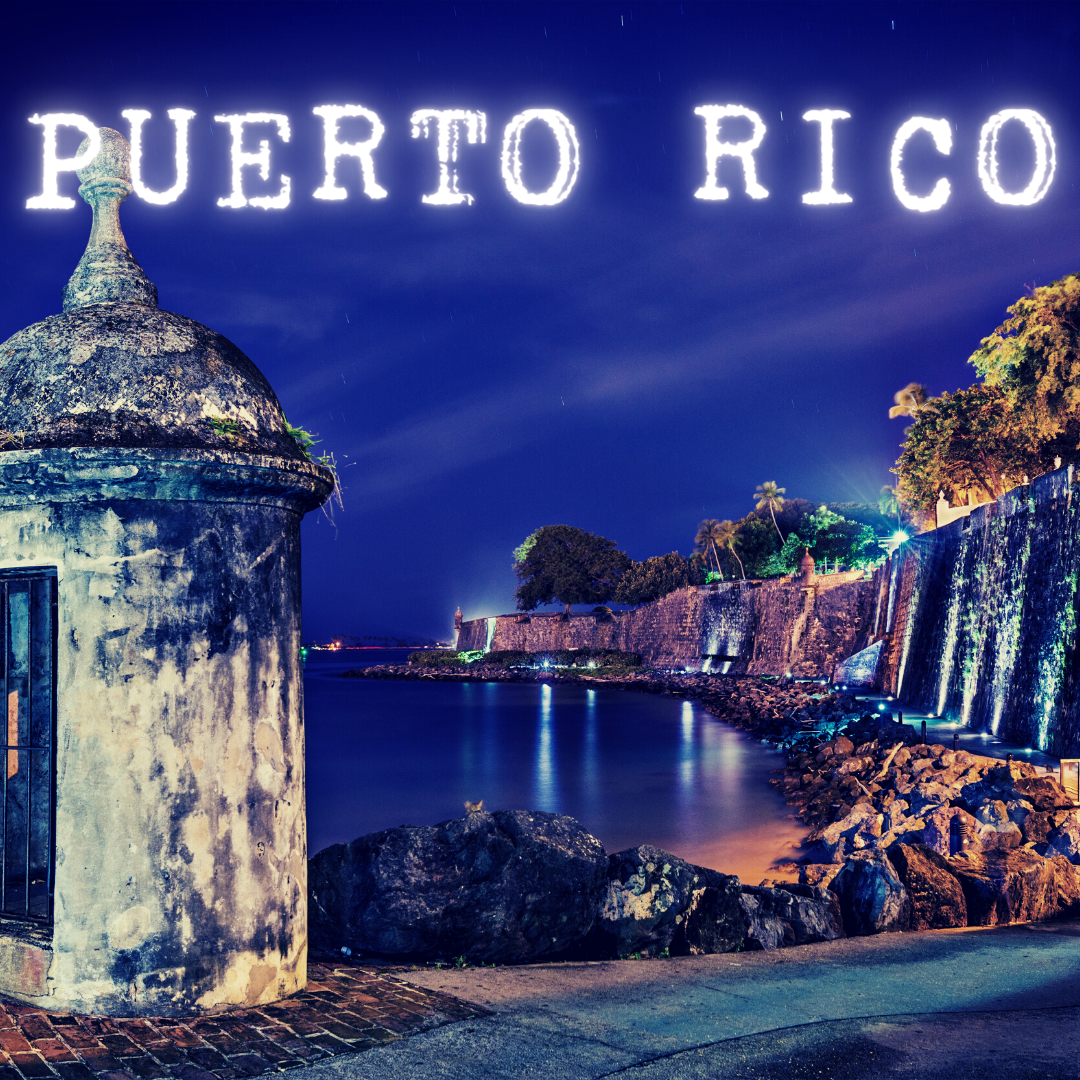 Nighttime view of Puerto Rico's coast with a fort, illuminated text "PUERTO RICO", and calm water reflecting lights.
