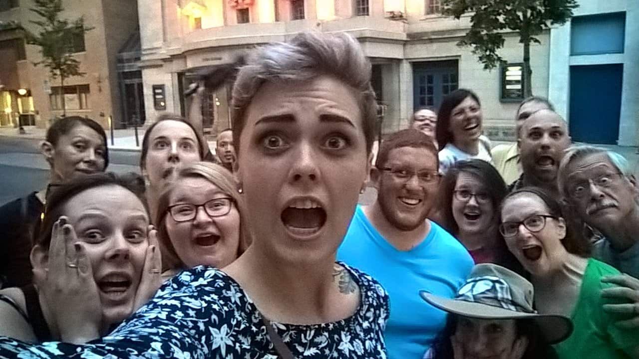 A group of people are posing for a selfie in front of a building.