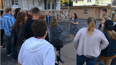 A woman is talking to a group of people in a parking lot.