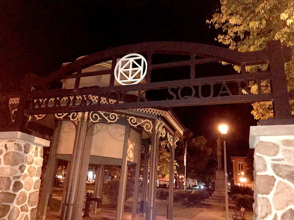 A sign for ivy city park square is lit up at night