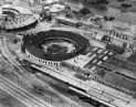 Aerial view of a train yard with a roundhouse, tracks, and trains in black and white.