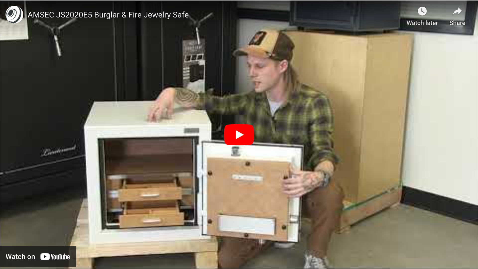 A man is holding a picture frame in front of a safe.
