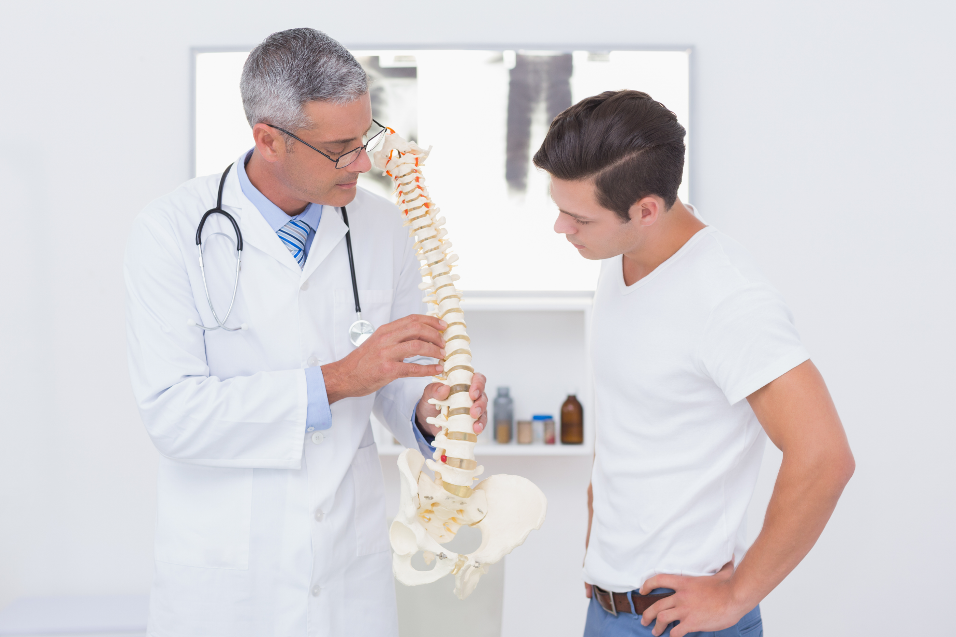 Chiropractor adjusting a patient lying face down on a treatment table in a clinic