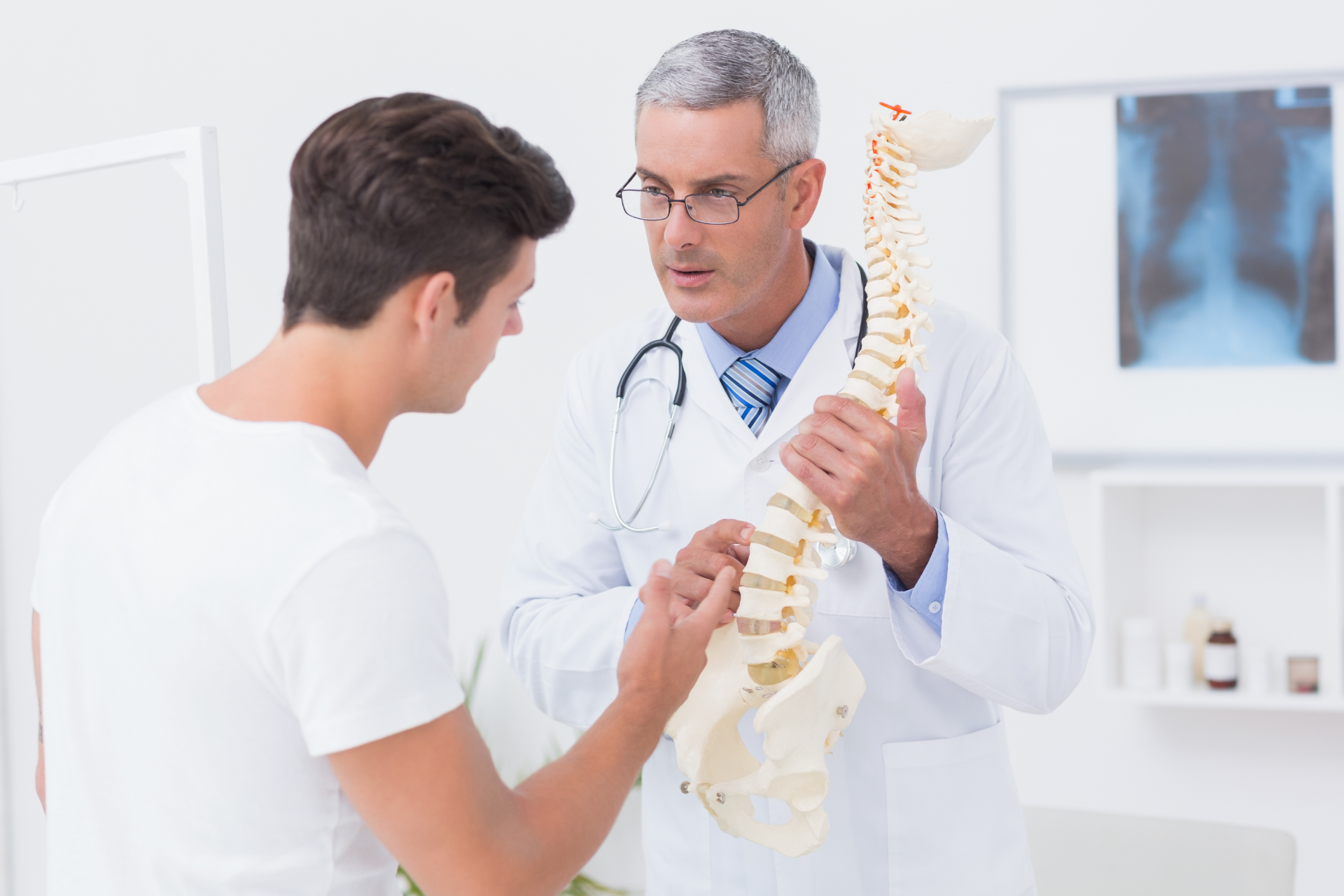 Chiropractor adjusting a patient lying face down on a treatment table in a clinic