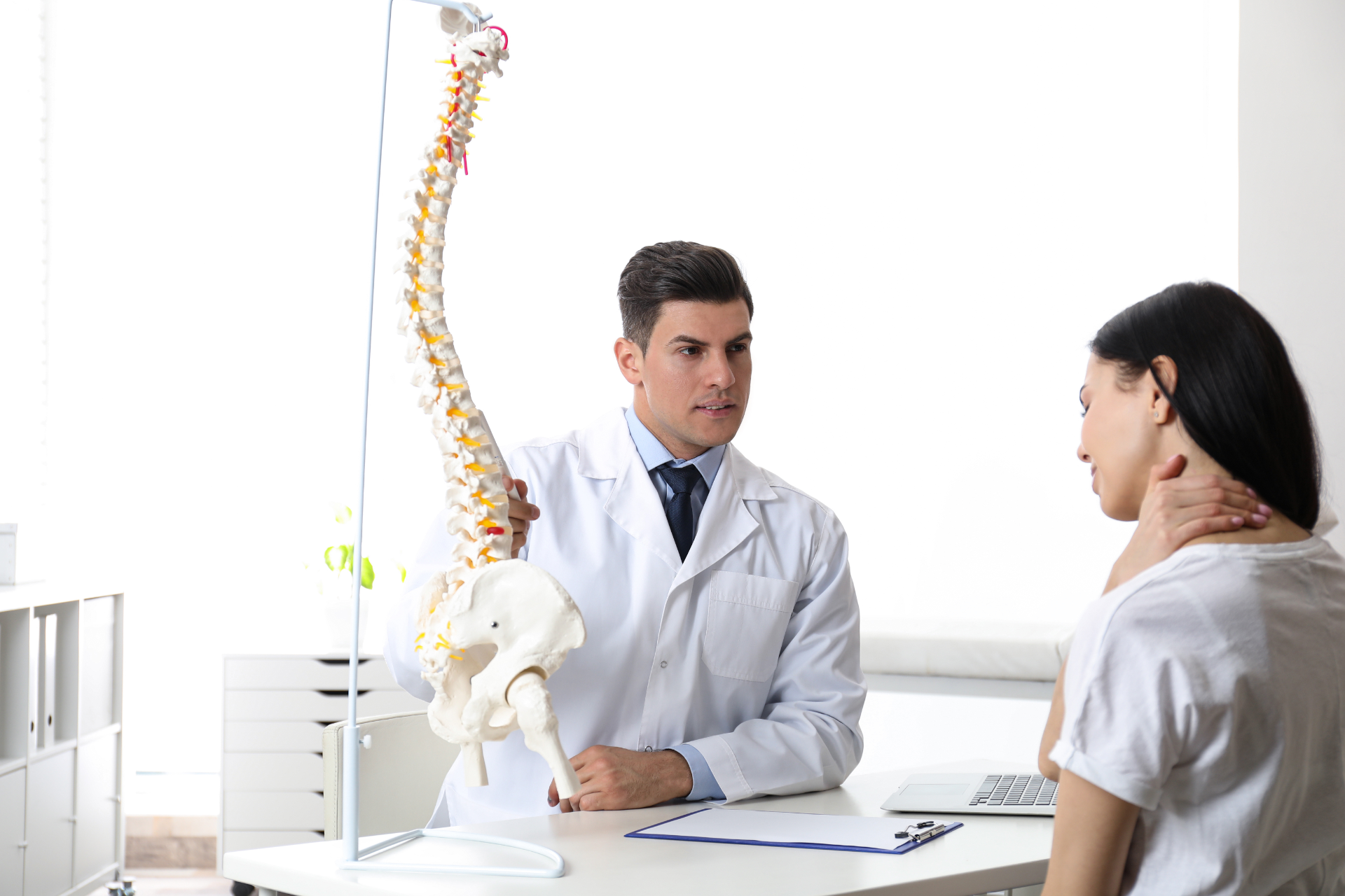 Chiropractor adjusting a patient lying face down on a treatment table in a clinic