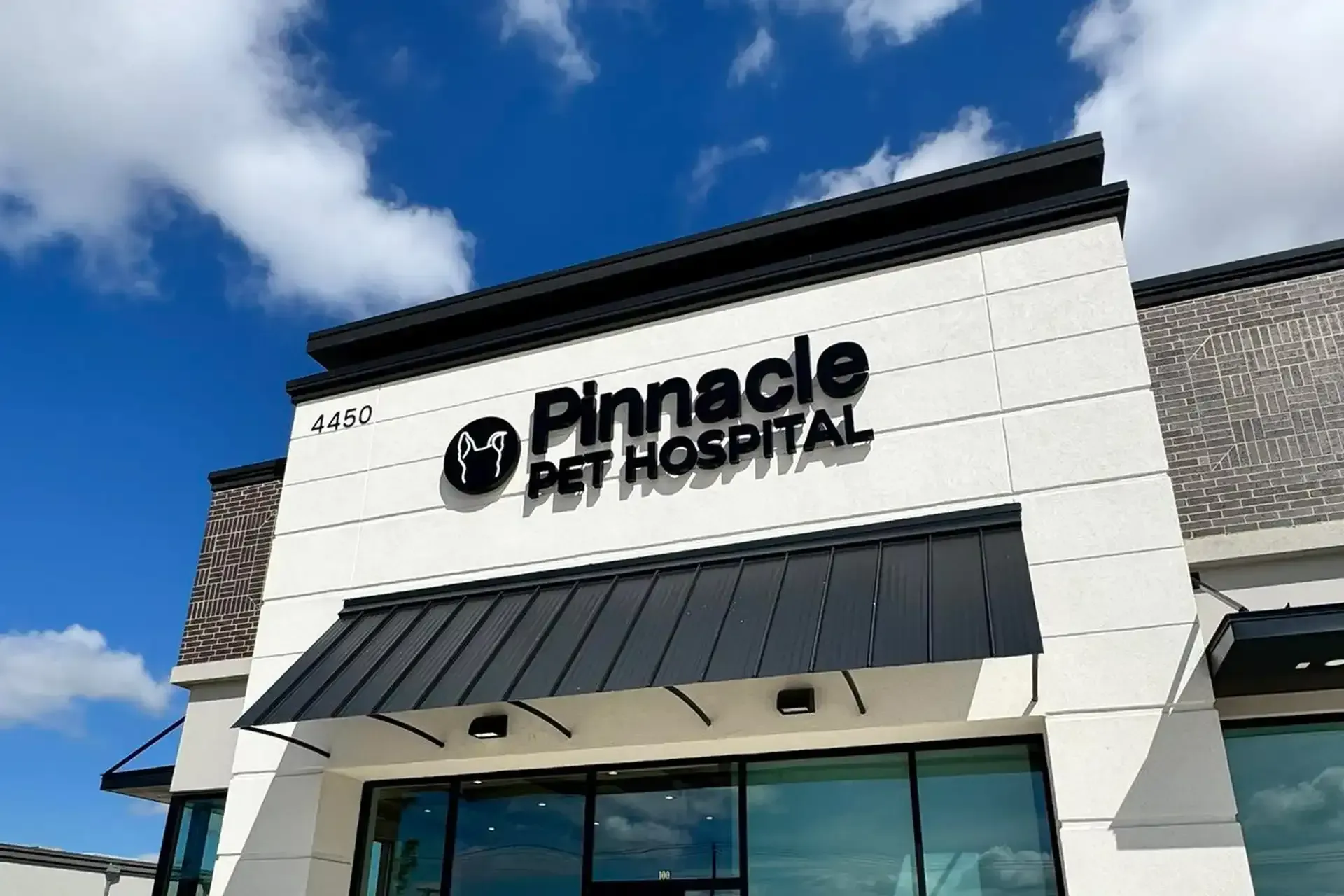 Pinnacle Pet Hospital storefront with white facade, black awning, and blue sky above