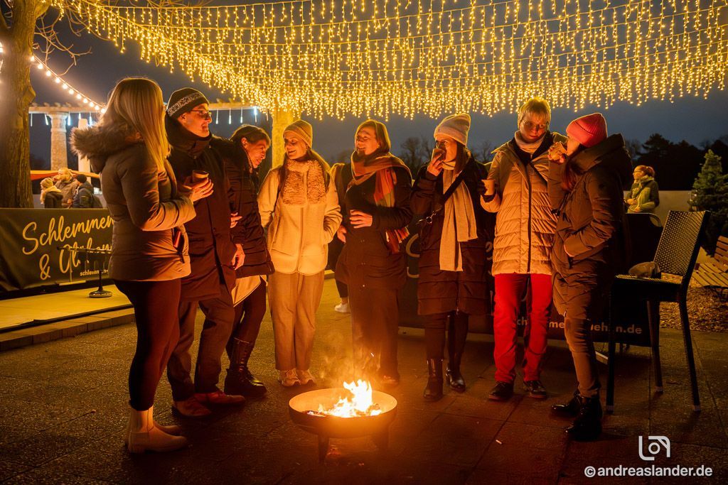 ollegen bei Weihnachtsfeier mit Glühwein in winterlicher Atmosphäre.