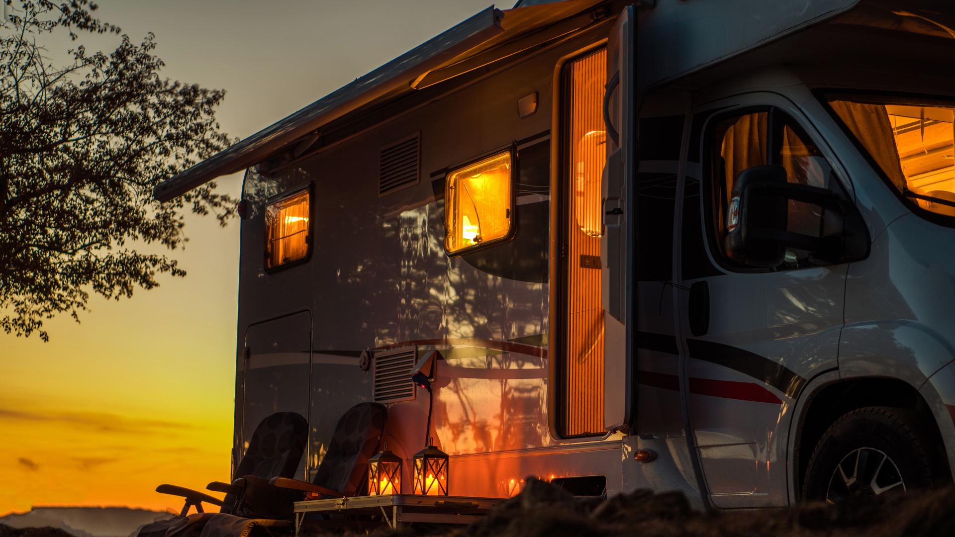RV parked at dusk with open door, illuminated interior, and ambient lanterns.