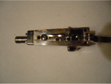 Silver metal firearm mechanism, disassembled on a white surface.