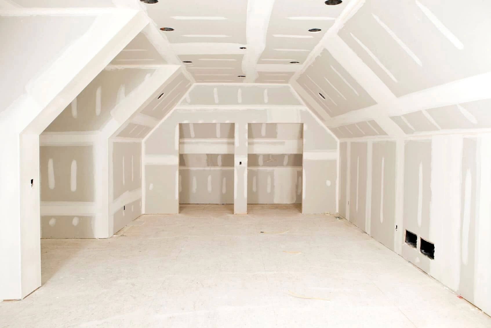 an empty room with a vaulted ceiling and drywall on the walls