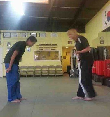 Two people bowing in a martial arts studio. Two people bowing in a martial arts studio.