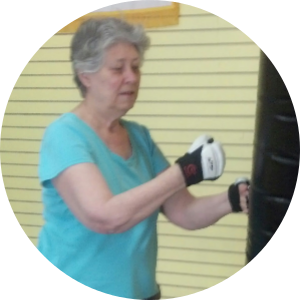 Woman in blue shirt boxing a punching bag.
