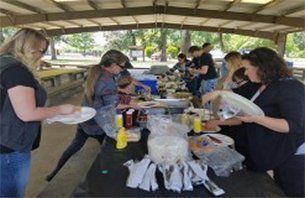 People at a picnic table under a covered pavilion.