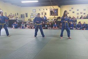 Three people in blue martial arts uniforms with yellow belts. Three people in blue martial arts uniforms with yellow belts.