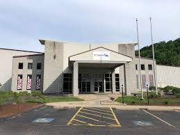 A commercial building exterior with a central entrance, gray facade, and two parking spaces for people with disabilities.