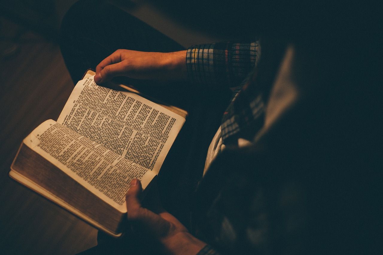 A person is reading a bible in a dark room.