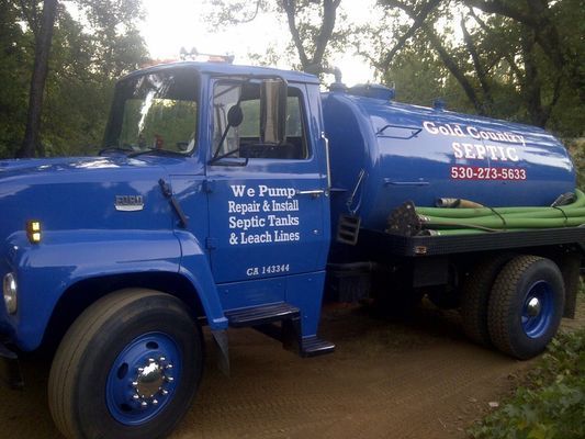 Blue septic service truck parked outdoors, with white and red lettering on the side.