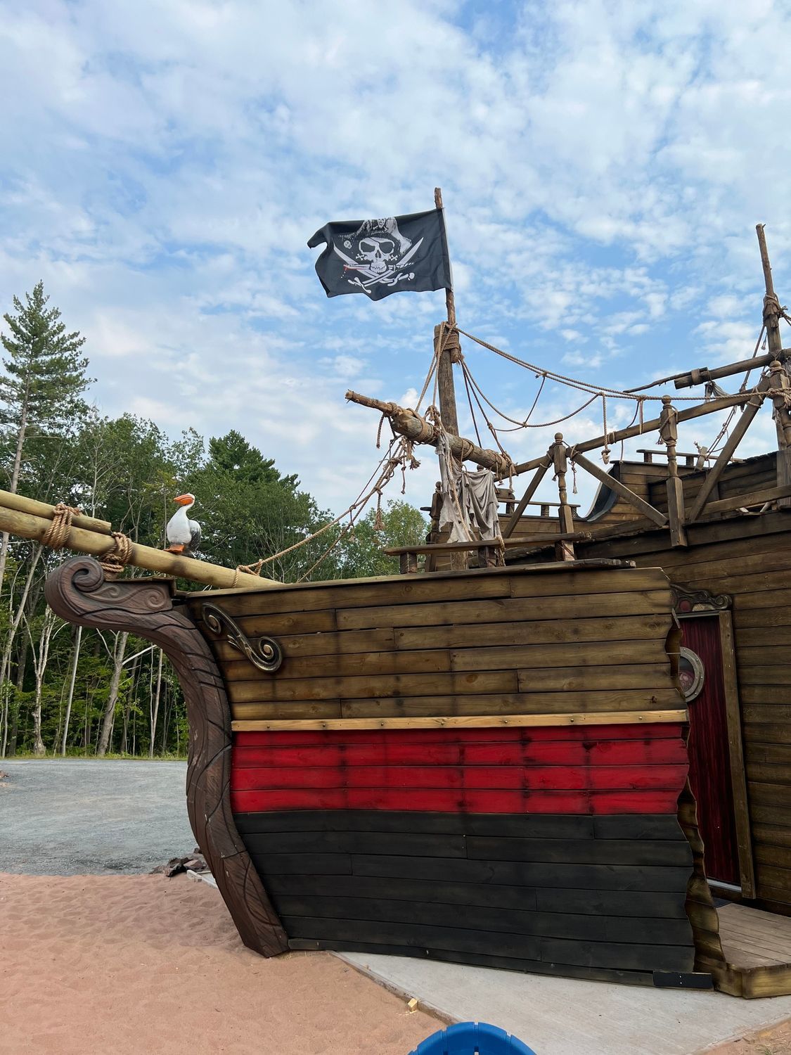 Pirate ship facade with black flag. Red and black paint on wooden exterior; cloudy sky backdrop.