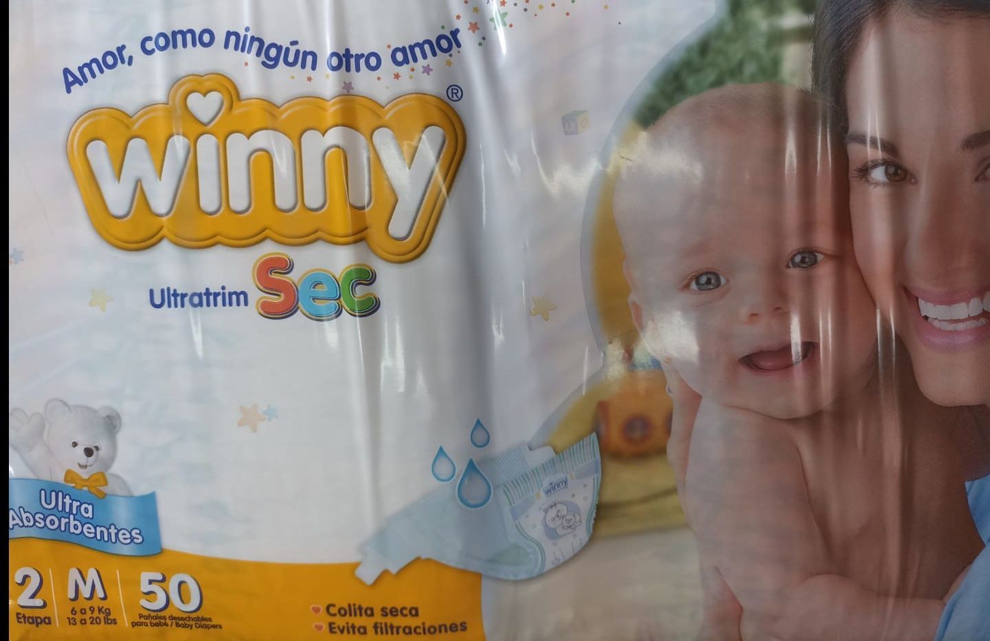 Paquete de pañales Winny Ultrathin Sec para bebé con padre e hijo sonrientes sobre fondo azul.