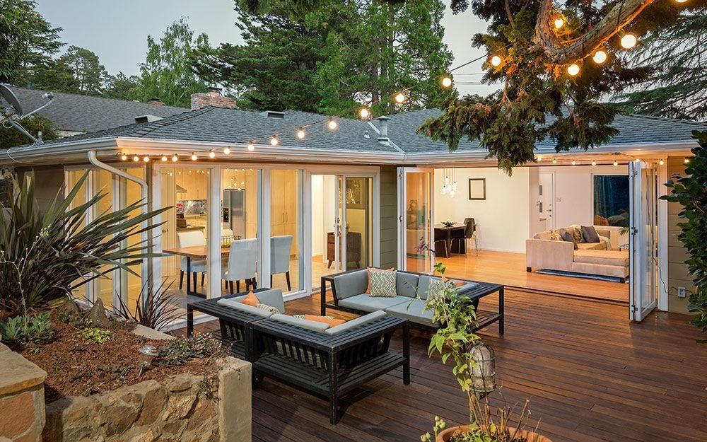 Backyard patio with string lights, outdoor sofas, and a dining area beside a house at dusk
