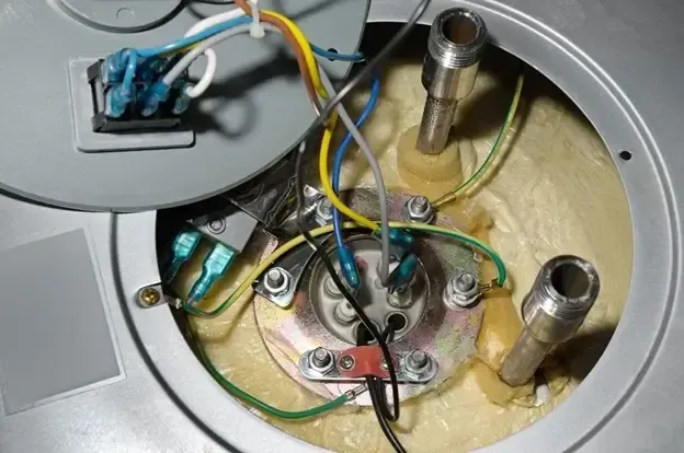 A water heater is sitting in a basement next to a wall.