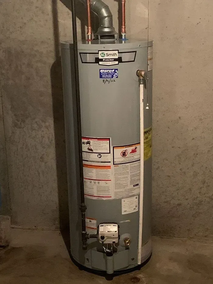 A water heater is sitting on the floor in a basement.