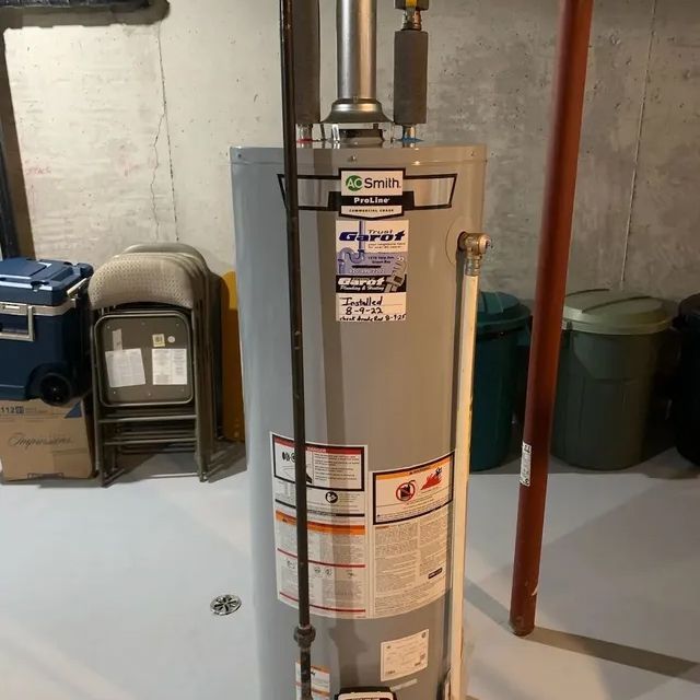 A water heater is sitting on the floor in a basement.
